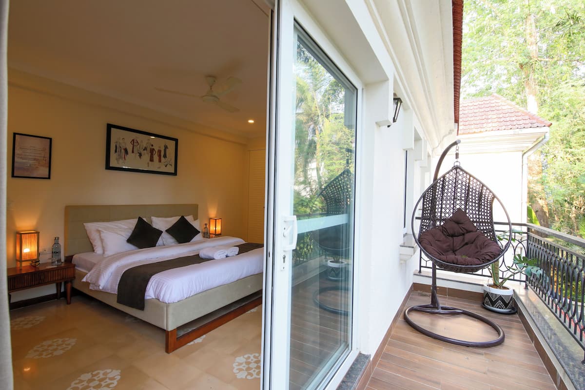 A bedroom with a bed, a nightstand, a ceiling fan, and a large window.