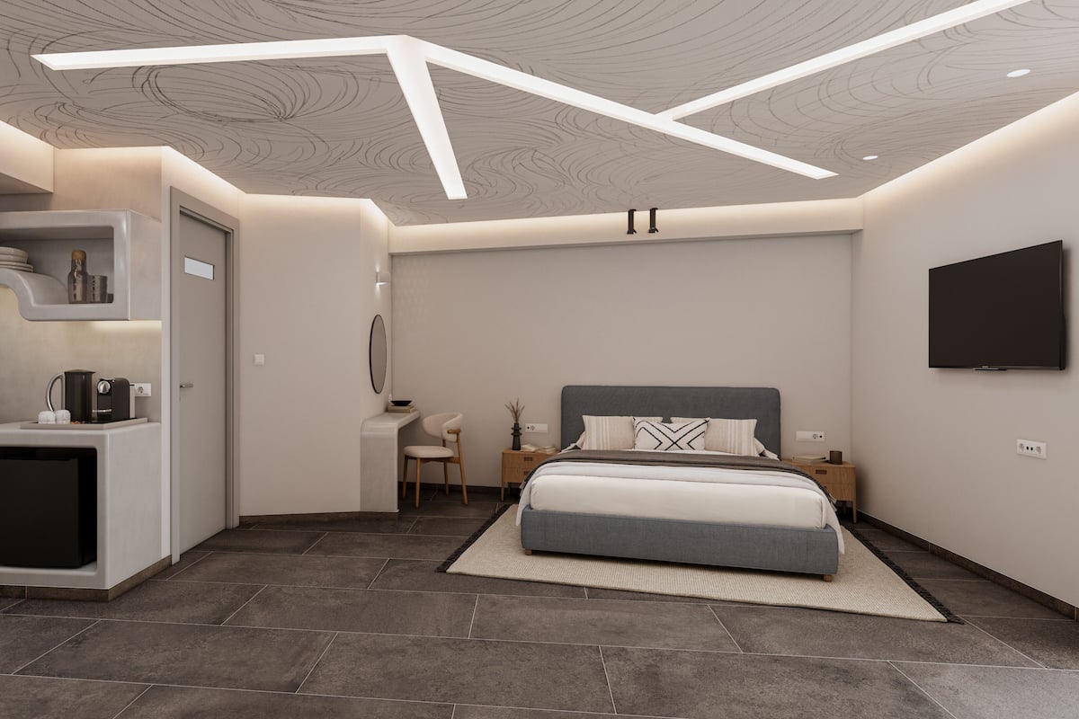 Ein modernes Schlafzimmer mit Bett, Nachttischen, Fernseher und einer integrierten Küchenzeile.