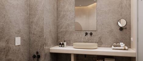 Un baño moderno con un lavabo color beige, un espejo redondo y un inodoro.