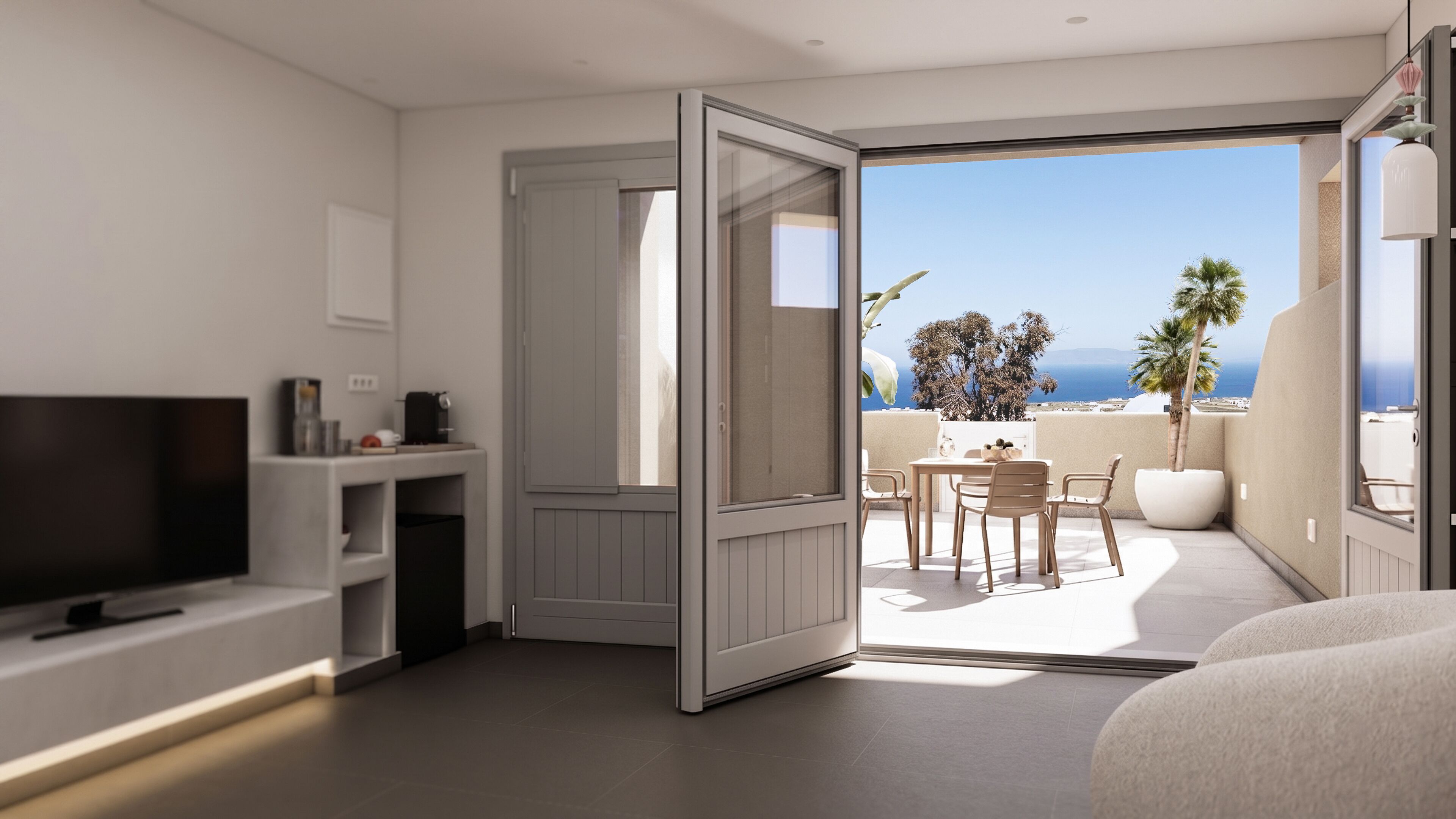 A modern hotel room with a TV, a small table with chairs, a balcony with a view of the sea, and a large window.