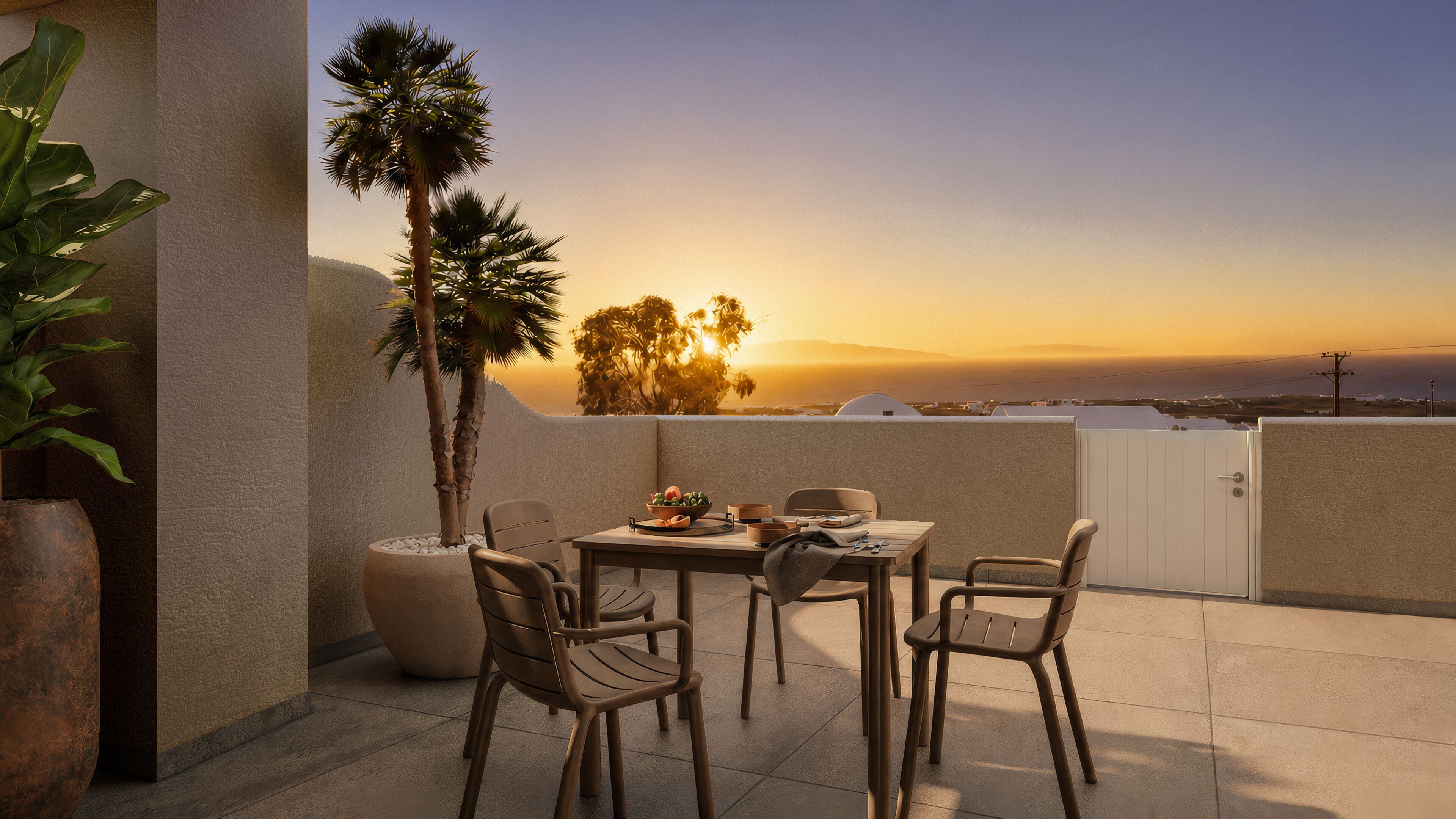 A terrace with a table and chairs, a potted plant, and a view of the sunset.