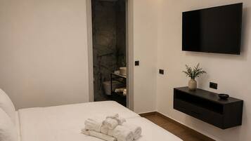 Een moderne slaapkamer met een bed, een televisie, een plank en een dakraam.