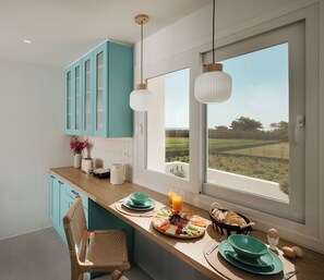 A modern kitchen with teal cabinets, a wooden countertop, and a breakfast spread including eggs, toast, and fruit. - Naxos Family Home in Kastraki – 3-Min Walk to Beach, Veranda, BBQ & Parking (Kastraki)