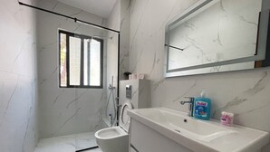 Ein Badezimmer mit Toilette, Bidet und Waschbecken, Marmorwänden und einem Fenster.