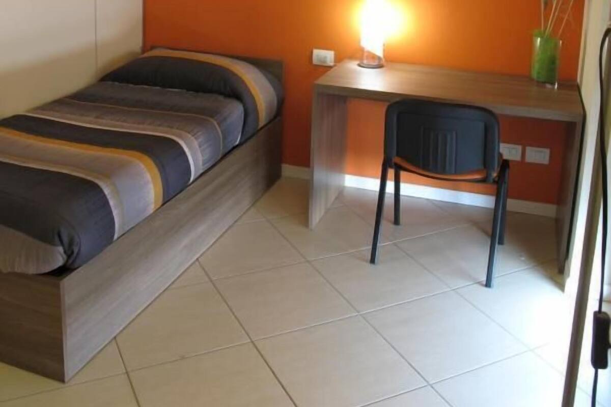 A room with a bed, a desk, and a chair.