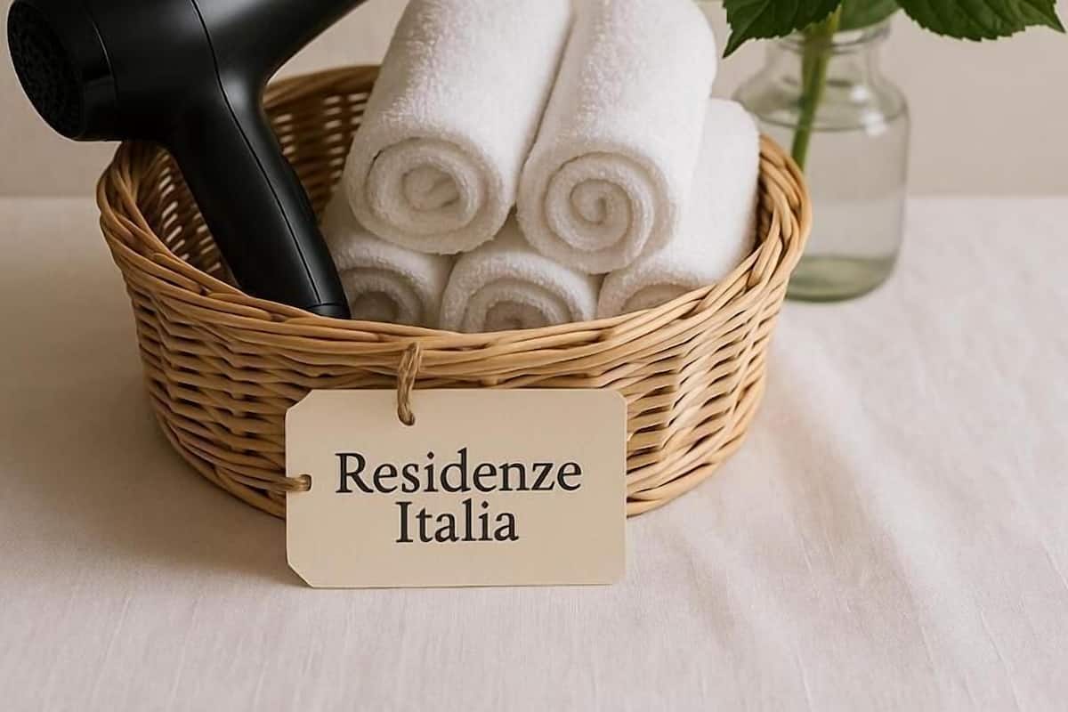 A wicker basket with a hairdryer, rolled towels, and a tag labeled 'Residenze Italia.'