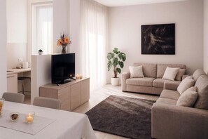 A modern living room with a sofa, TV, and a plant.