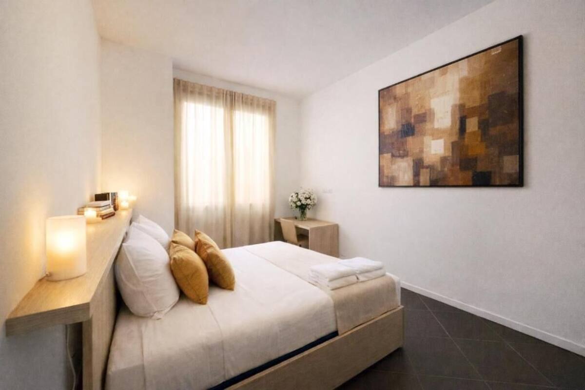 A modern bedroom with a bed, bedside table, and a large abstract painting on the wall.