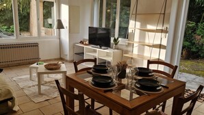 A dining area with a table set for four, a television, and a view of the outdoors.