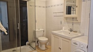 A bathroom with a toilet, sink, and washing machine.