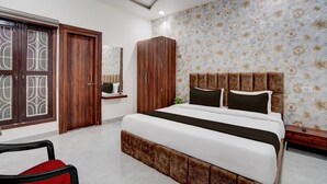 A bedroom with a large bed, wooden wardrobe, and a mirror. - Super Deluxe Room Neelam Hotel (Bareilly)