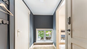 Um corredor com vista para uma varanda, uma porta com fechadura eletrônica e um porta-roupas.