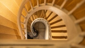 Uma escadaria em espiral com corrimão branco e um pilar central.