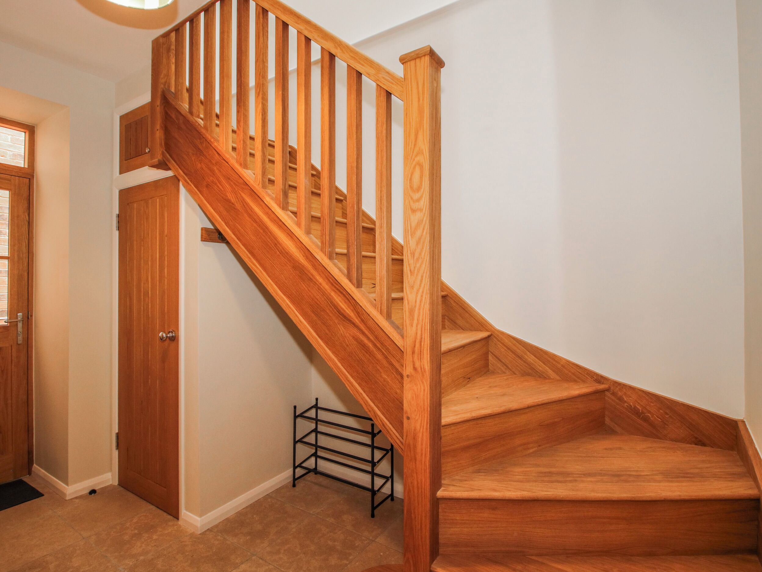 A wooden staircase with a handrail, leading to a landing.