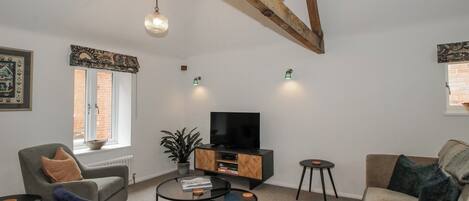 A living room with a sofa, armchair, coffee table, TV, and decorative items.