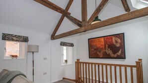 Ett rum med ett sluttande tak, ett träräcke, en soffa, en lampa och en tavla.