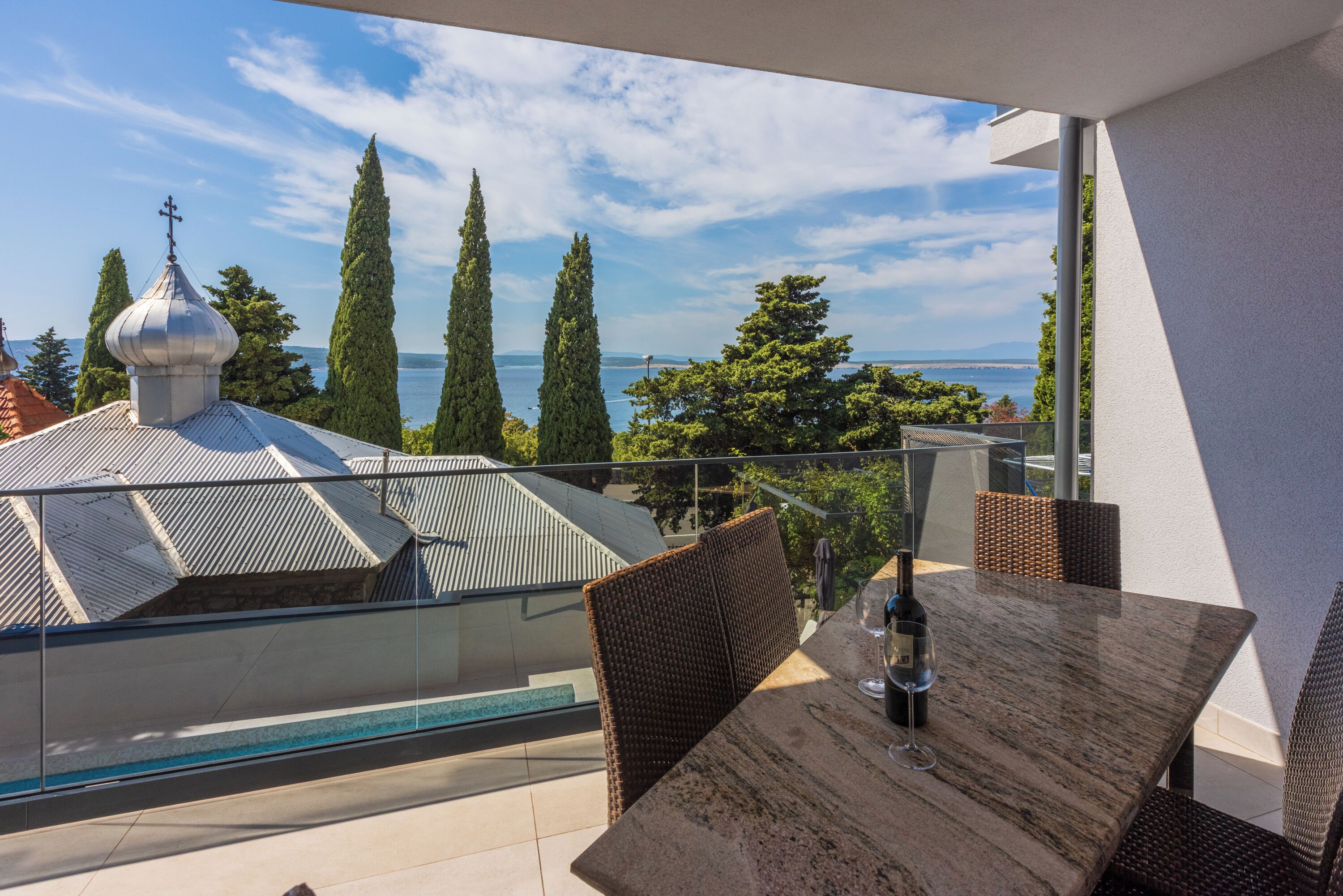 Ein Balkon mit Tisch, Stühlen und einer Weinflasche.