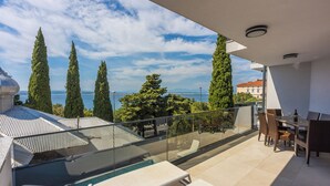 Un balcó amb piscina, mobles d'exterior i vista al mar i als arbres.