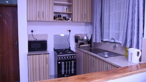 Une cuisine compacte équipée d’un four à micro-ondes, d’une cuisinière, d’un évier et d’une bouilloire.