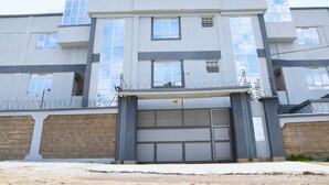 Un immeuble à plusieurs étages doté d’une porte de garage, de fils barbelés sur le toit et d’un mur en briques.