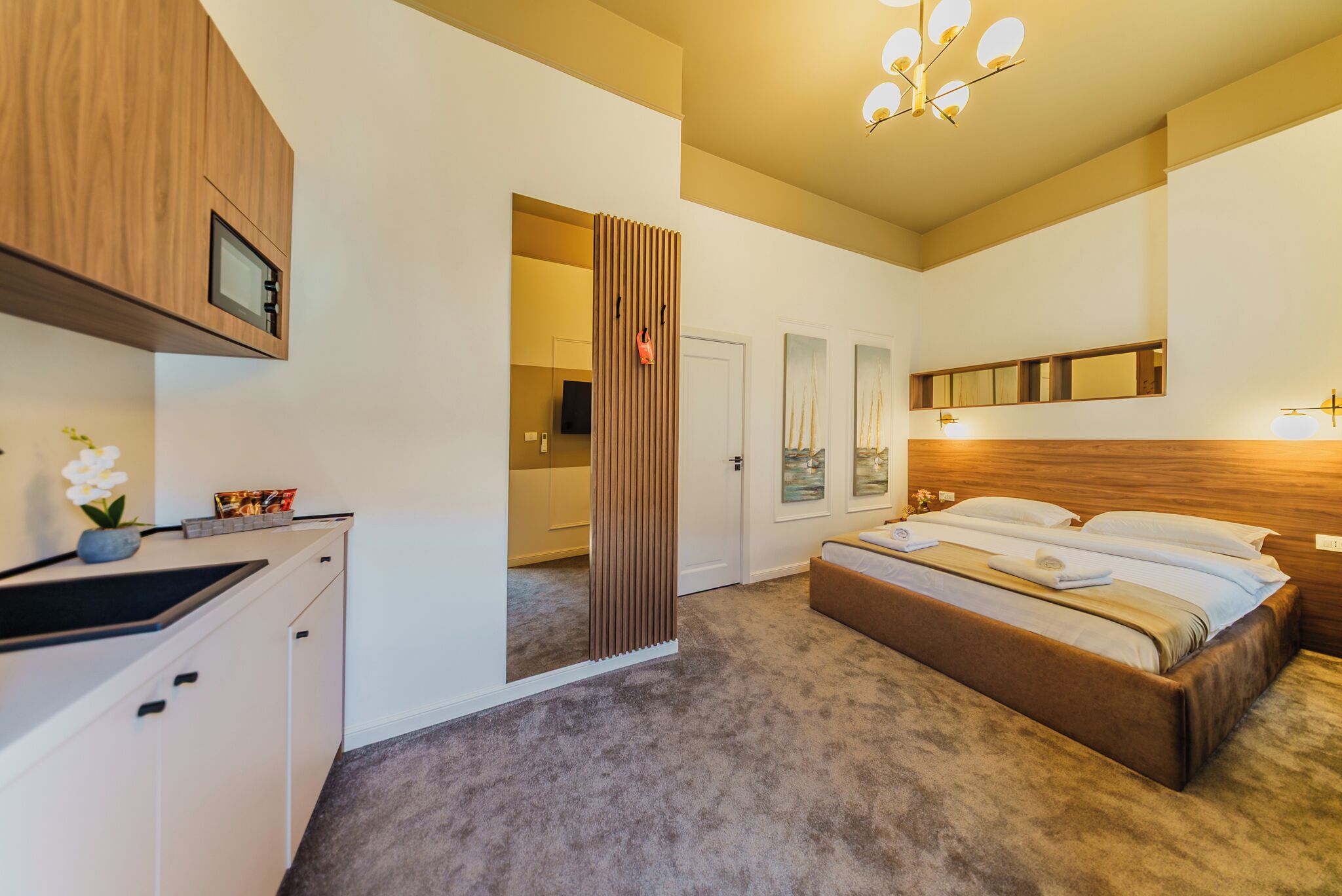 Una camera da letto con un letto, un armadietto in legno, uno specchio e una porta che dà su un'altra stanza.