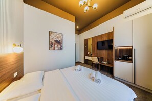 Une chambre d’hôtel équipée d’un lit, d’un bureau, d’une télévision et d’une kitchenette.