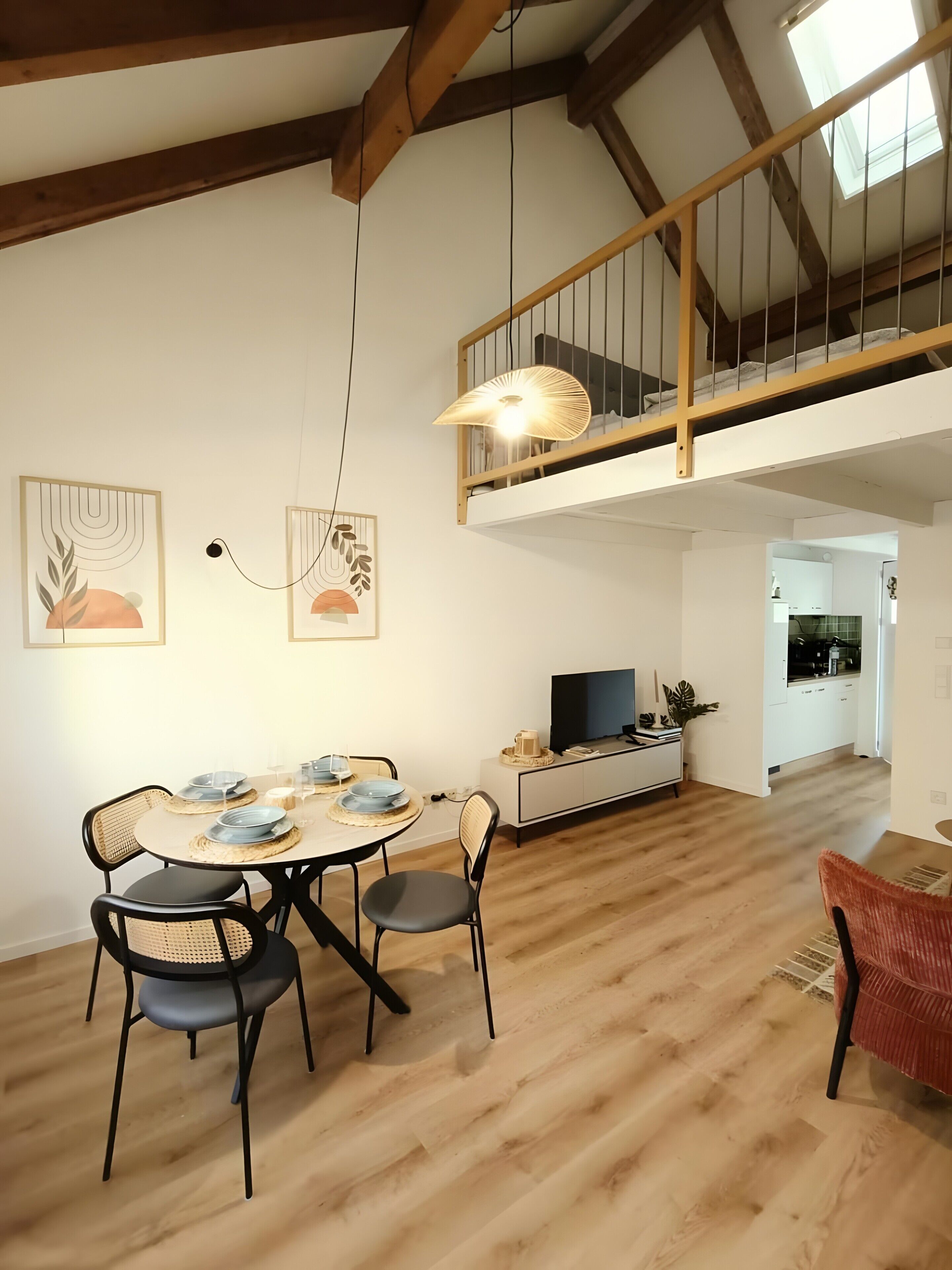 Un coin repas avec une table, des chaises et un téléviseur posé sur un meuble blanc.