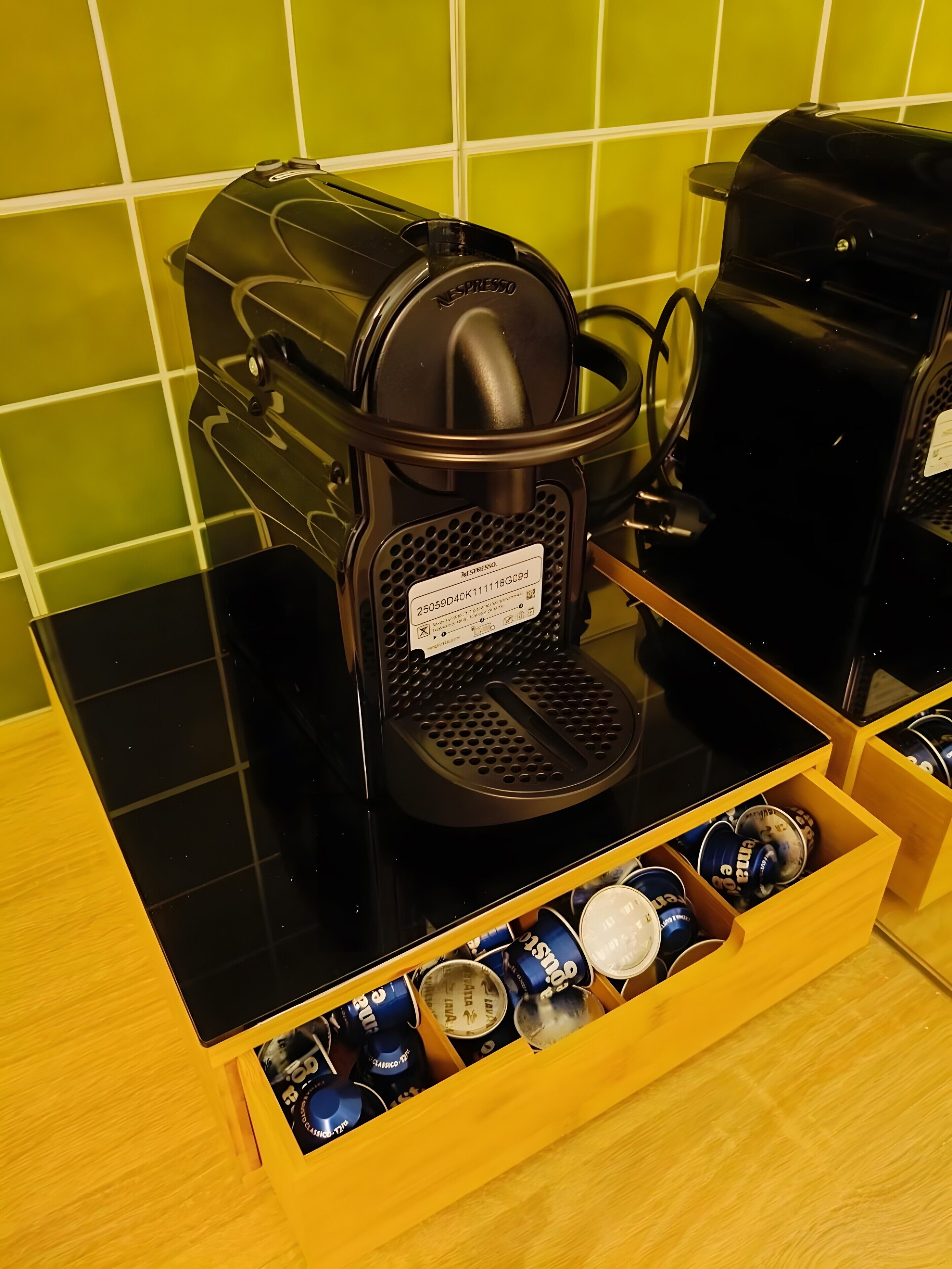 A Nespresso coffee machine on a black countertop with a drawer containing coffee capsules.