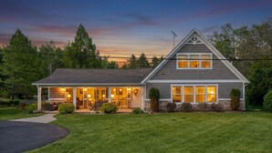 Une maison à deux étages avec un porche couvert, une allée et une pelouse bien entretenue.