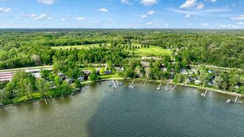 An aerial view of a lakeside community with residential buildings, a marina, and surrounding greenery.