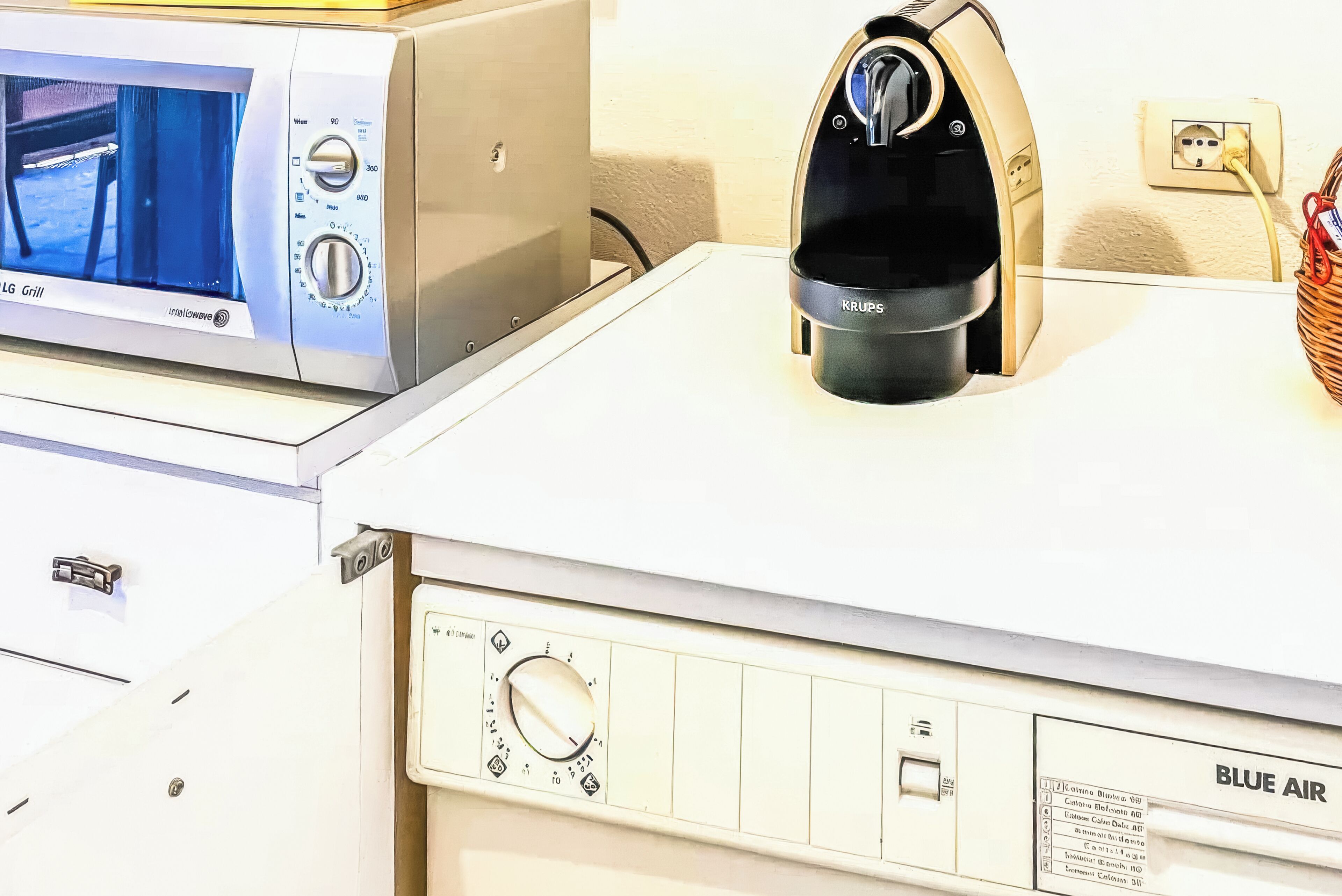 A kitchen with a microwave, coffee maker, and a control panel with a dial.