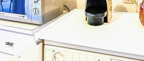 A kitchen with a microwave, coffee maker, and a control panel with a dial.