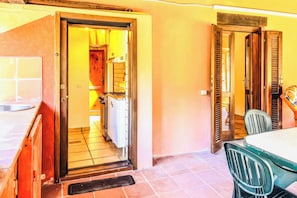 A room with a tiled floor, a sink, a window, and a door leading to another room. - Alloggio privato AS (San Teodoro)