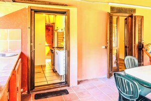Una habitación con suelo de baldosas, un lavabo, una ventana y una puerta que da a otra estancia.