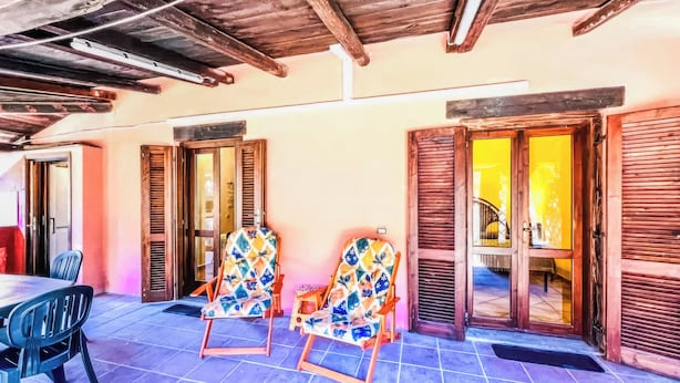 A patio with two rocking chairs, a table, and a tiled floor. - Alloggio privato AS (San Teodoro)