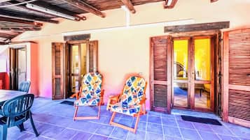 A patio with two rocking chairs, a table, and a tiled floor.