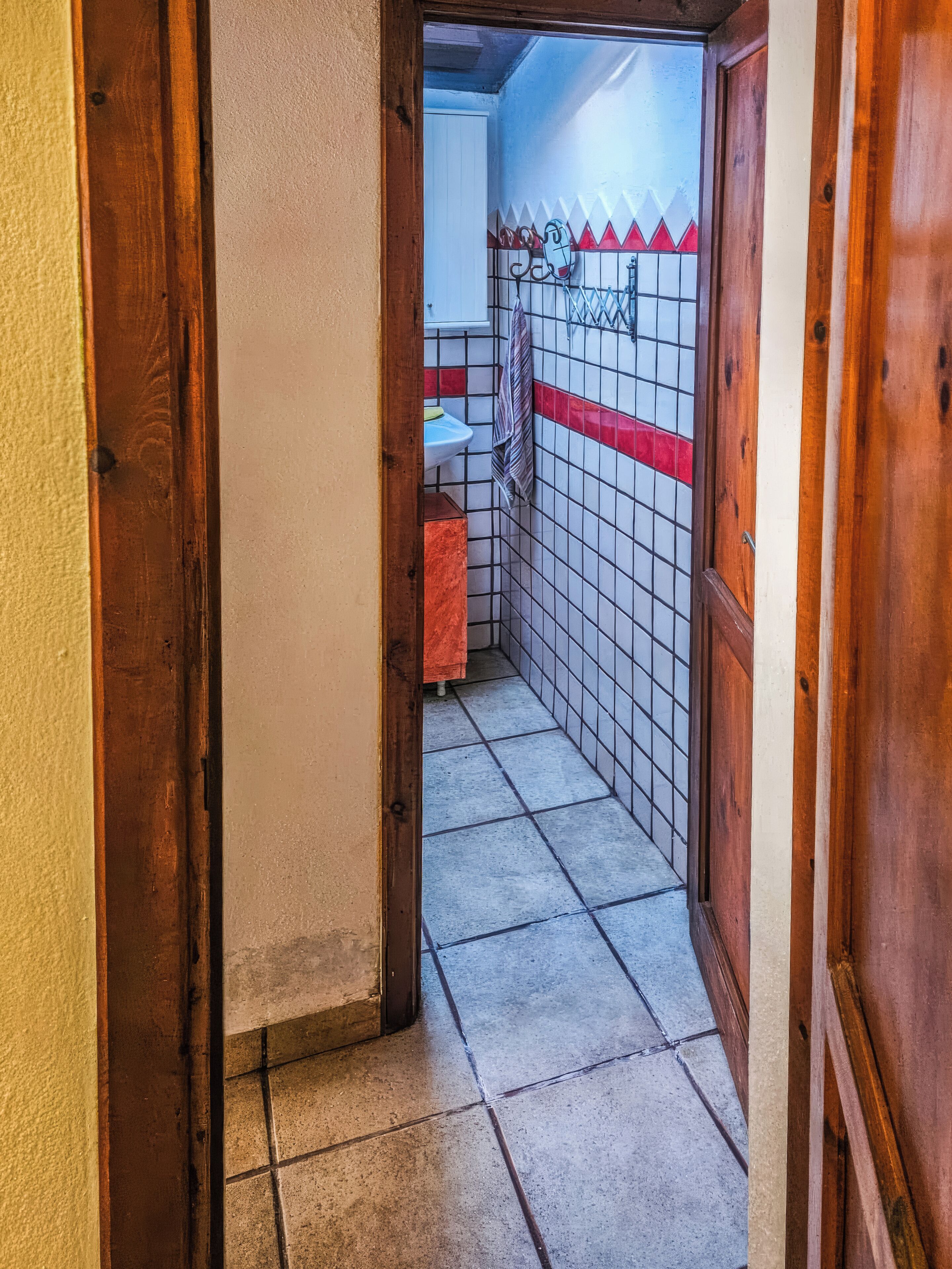 A narrow hallway with tiled walls and a wooden door frame.