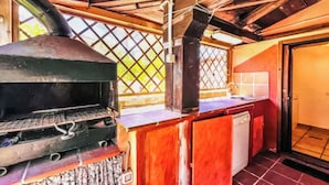 A rustic outdoor kitchen with a grill, a sink, and a wooden structure. - Alloggio privato AS (San Teodoro)