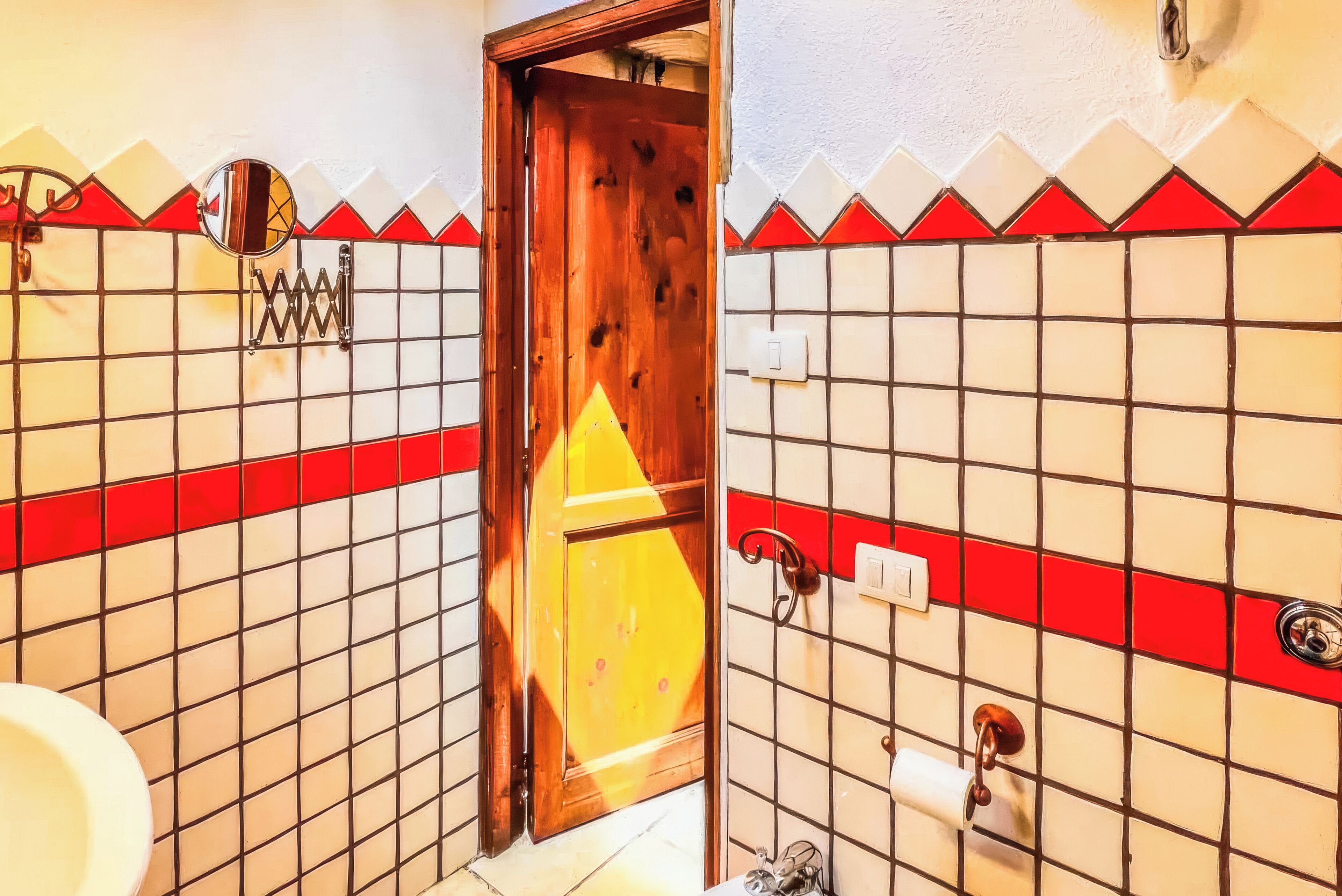 A bathroom with a wooden door, tiled walls, and a mirror.