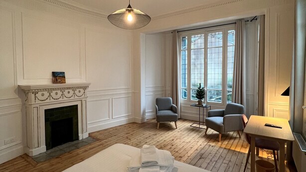 A hotel room with a fireplace, a bed, two armchairs, a small table, and a large window. - Finestate Coliving Dupleix (Paris)