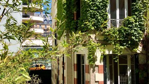 A building with a narrow alleyway, a balcony with metal railings, and a window with a grid pattern. - Finestate Coliving Dupleix (Paris)