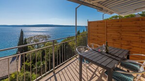 A balcony with a table and chairs, overlooking a body of water and distant hills. - Apartment with sea view in Crikvenica - ideal for 2-4 persons, with pool (Crikvenica)