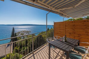 A balcony with a table and chairs, overlooking a body of water and distant hills. - Apartment with sea view in Crikvenica - ideal for 2-4 persons, with pool (Crikvenica)