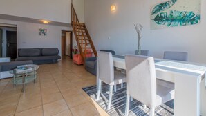 A modern living room with a sofa, coffee table, dining table, chairs, and a staircase. - Apartment with sea view in Crikvenica - ideal for 2-4 persons, with pool (Crikvenica)
