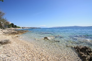 A pebble beach with clear water, a rocky shoreline, and distant mountains. - Apartment with sea view in Crikvenica - ideal for 2-4 persons, with pool (Crikvenica)