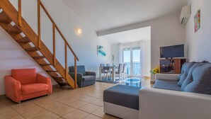 A living room with a staircase, a sofa, a coffee table, and a TV. - Apartment with sea view in Crikvenica - ideal for 2-4 persons, with pool (Crikvenica)