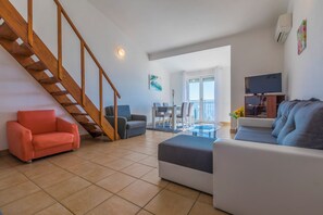 A living room with a staircase, a sofa, a coffee table, and a TV. - Apartment with sea view in Crikvenica - ideal for 2-4 persons, with pool (Crikvenica)