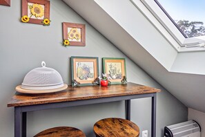 A room with a sloped ceiling, a table with a white object on it, and two framed pictures with sunflowers. - Apartment -Sorayas Welt- direkt hinter dem Deich mit allen Annehmlichkeiten (Neufeld)