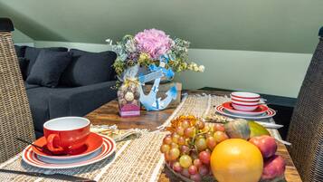 Una mesa de comedor con un frutero, una taza roja y un plato de galletas.