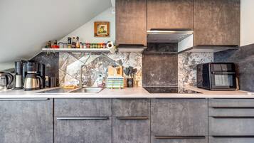 Una cocina moderna con gabinetes oscuros, salpicadero de mármol y electrodomésticos de acero inoxidable.